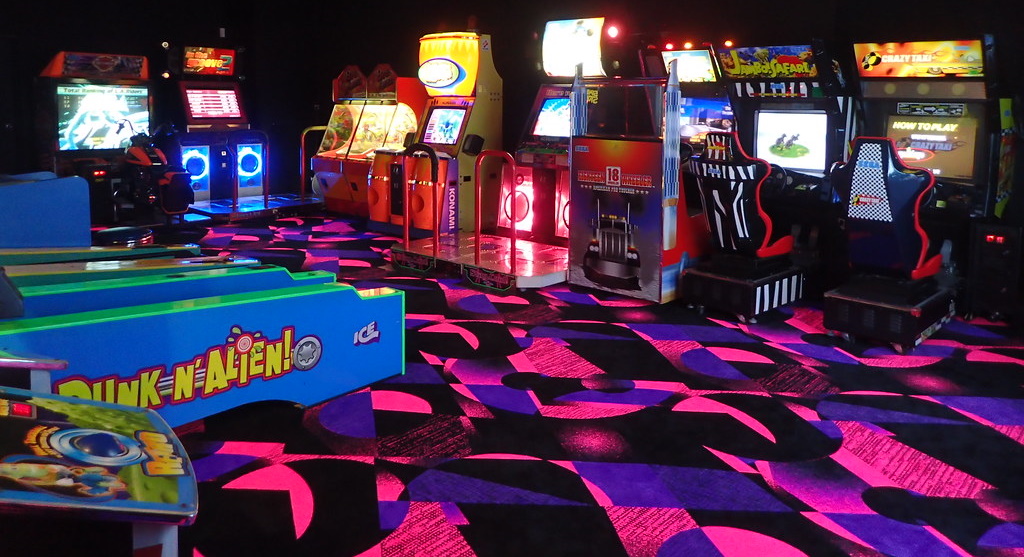 dark room with blue and purple patterned carpet and arcade games